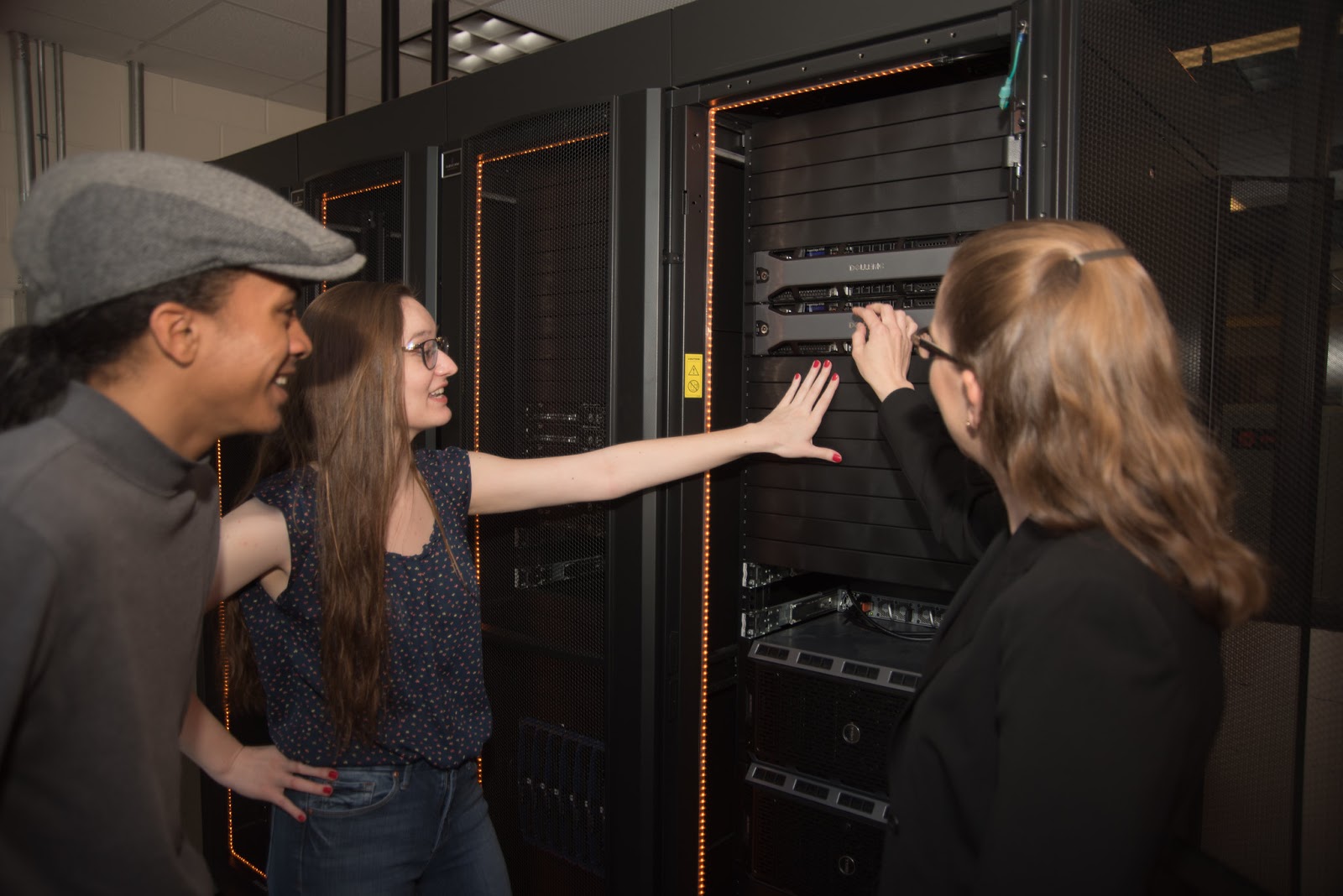Two students and a professor look at computer servers