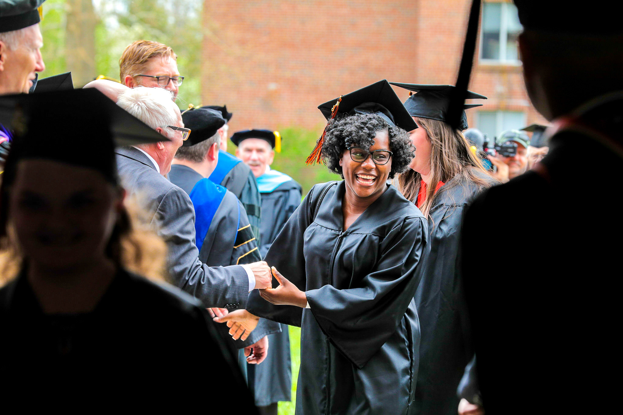 graduated woman shaking hands with faculty and staff
