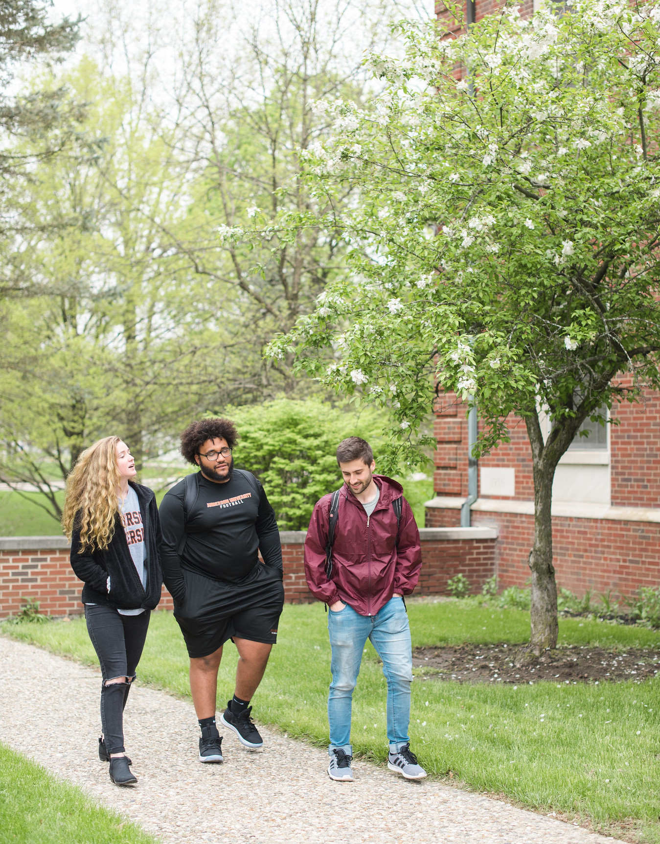Three students walking in front of the library.