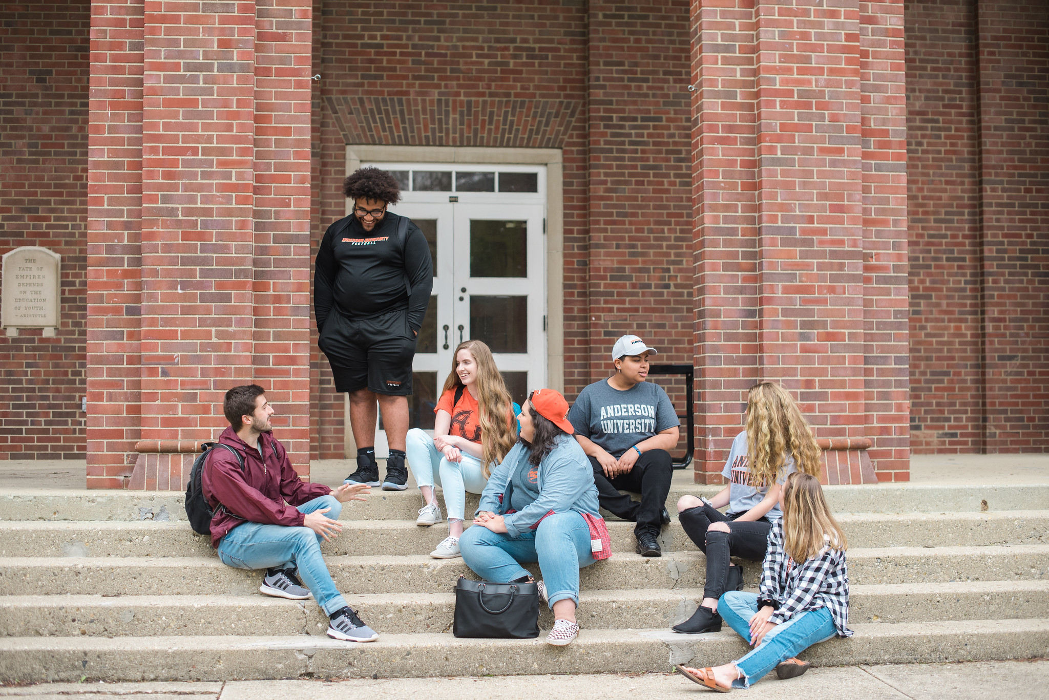Seven students sitting outside on steps on the Anderson University campus