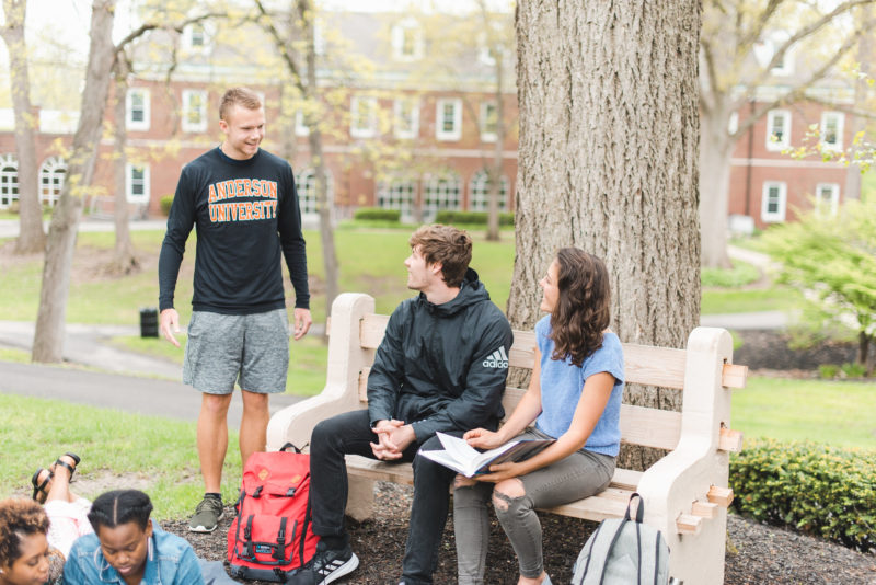 Five students gathered around a bench in the Valley at Anderson University
