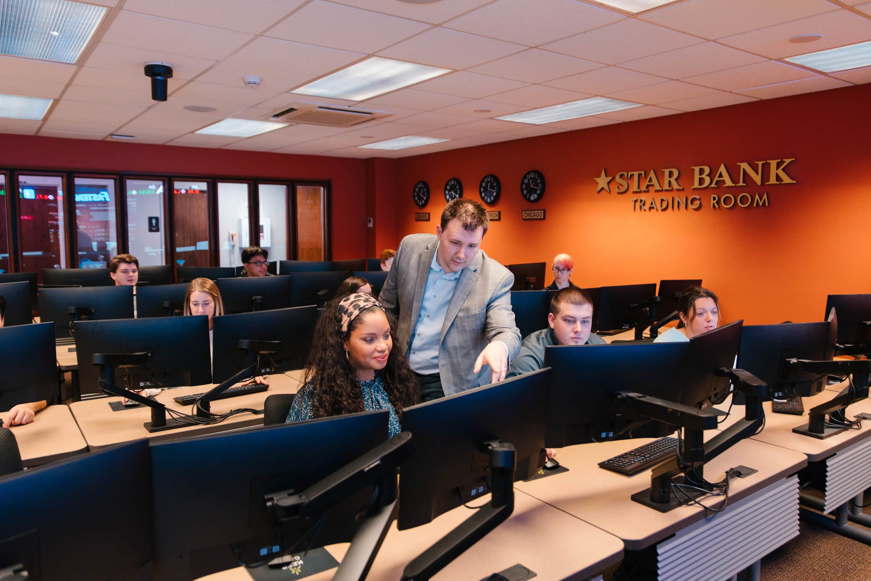 A professor instructing students in the Star Trading Lab