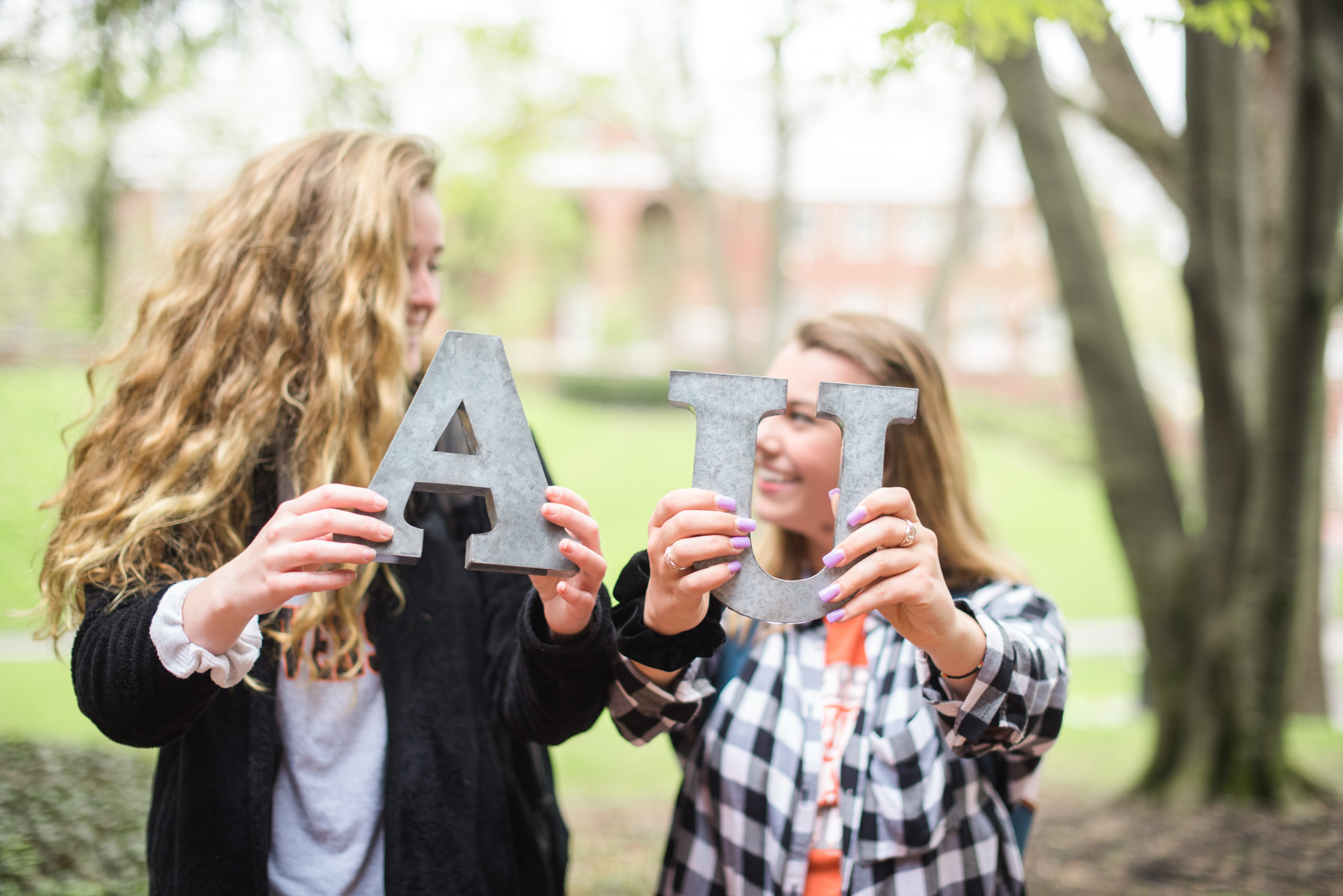 Two students holding the letters "A" and "U".