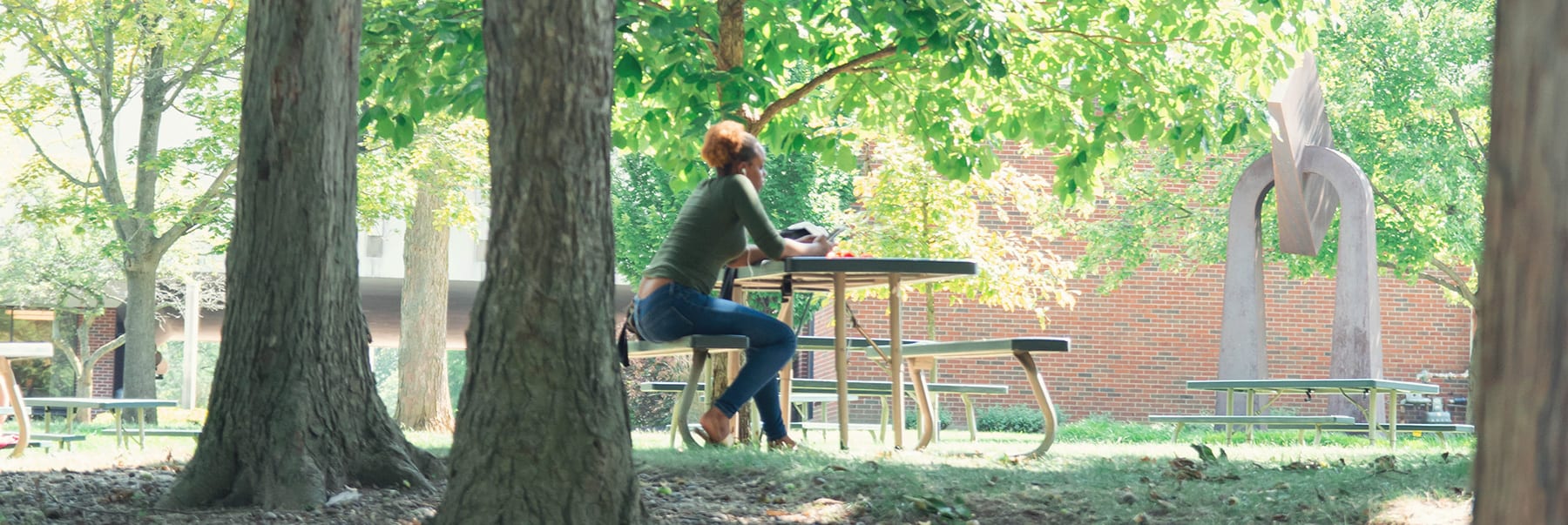 female student sitting on picnic table studying