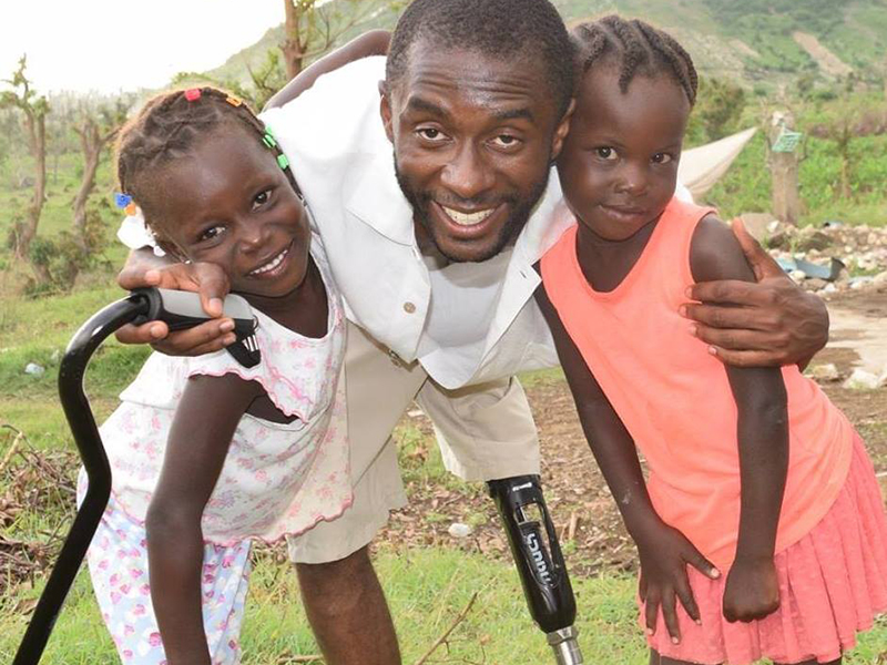 Ralf Etienne poses with two young girls in Haiti