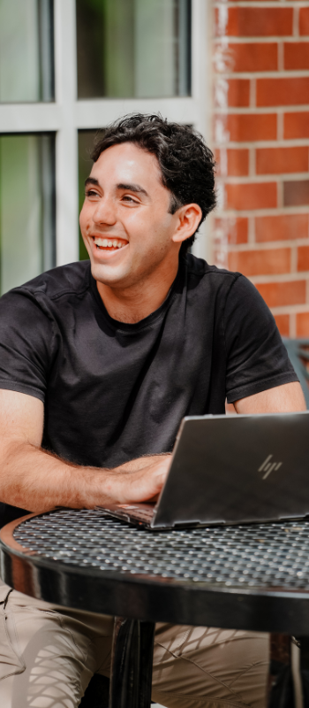 Set 2 Vertical Website Images 350x800 (5) A student sitting at an outside table