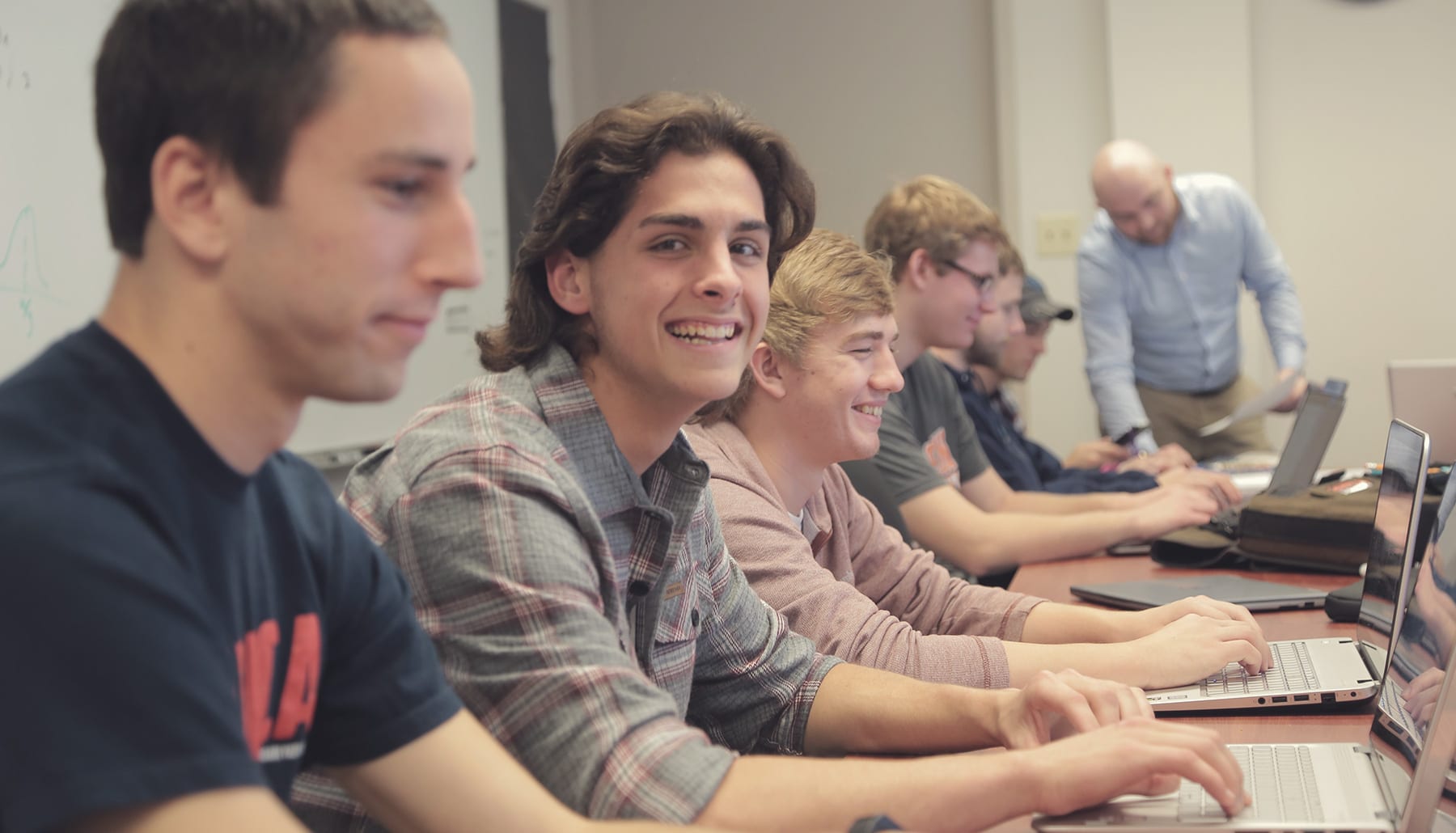 Student smiling while at his computer in class