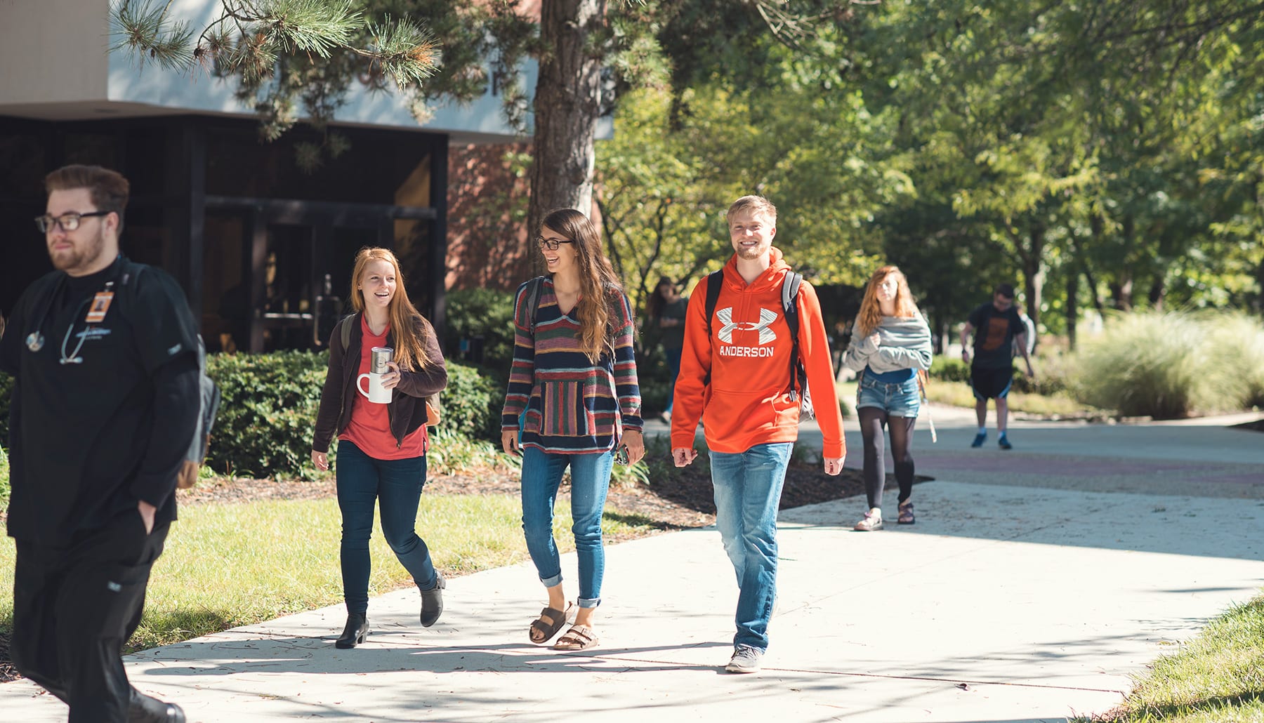 6 students walking to class in sunny sidewalk