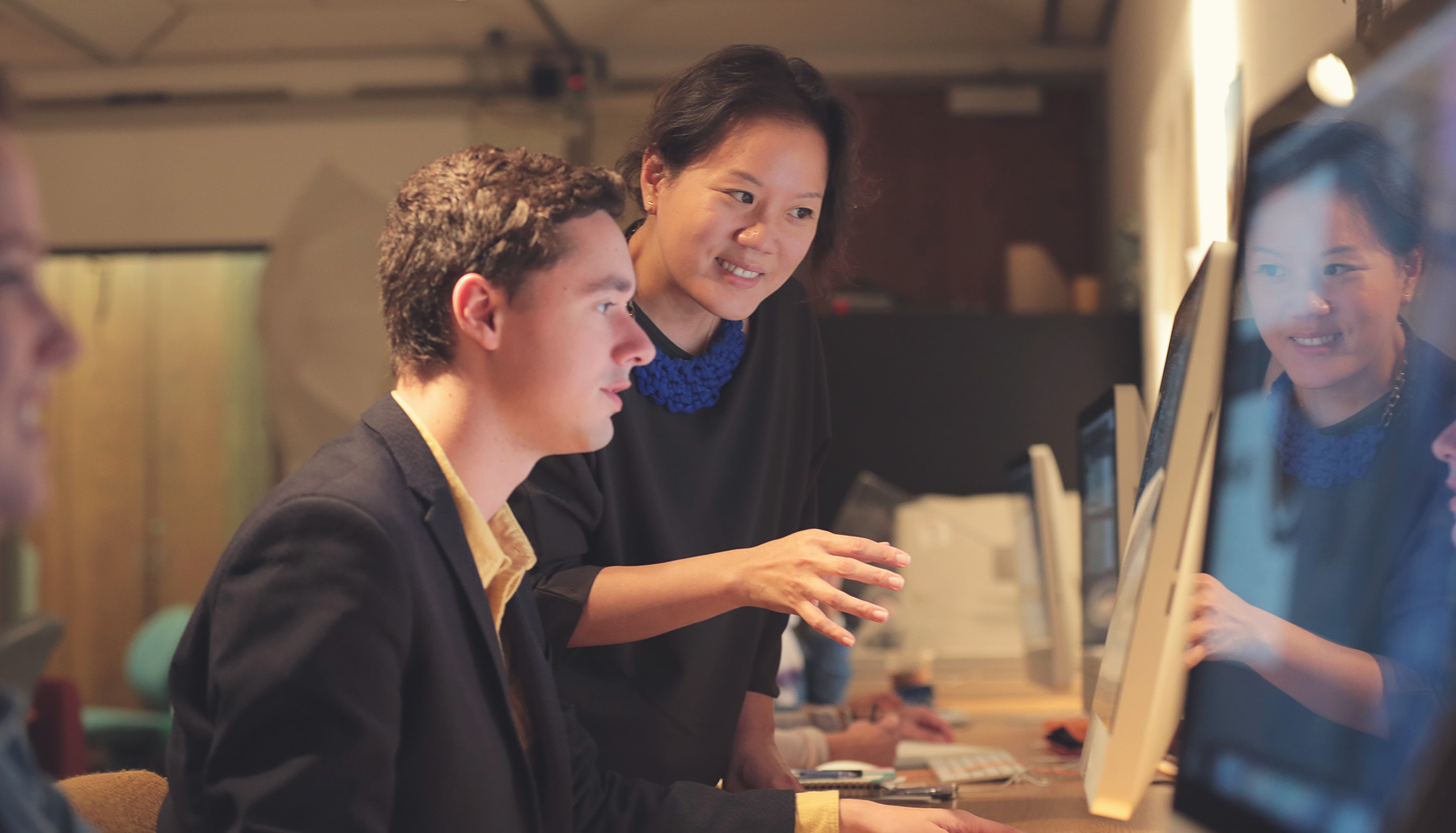 a professor works with a student in a computer lab