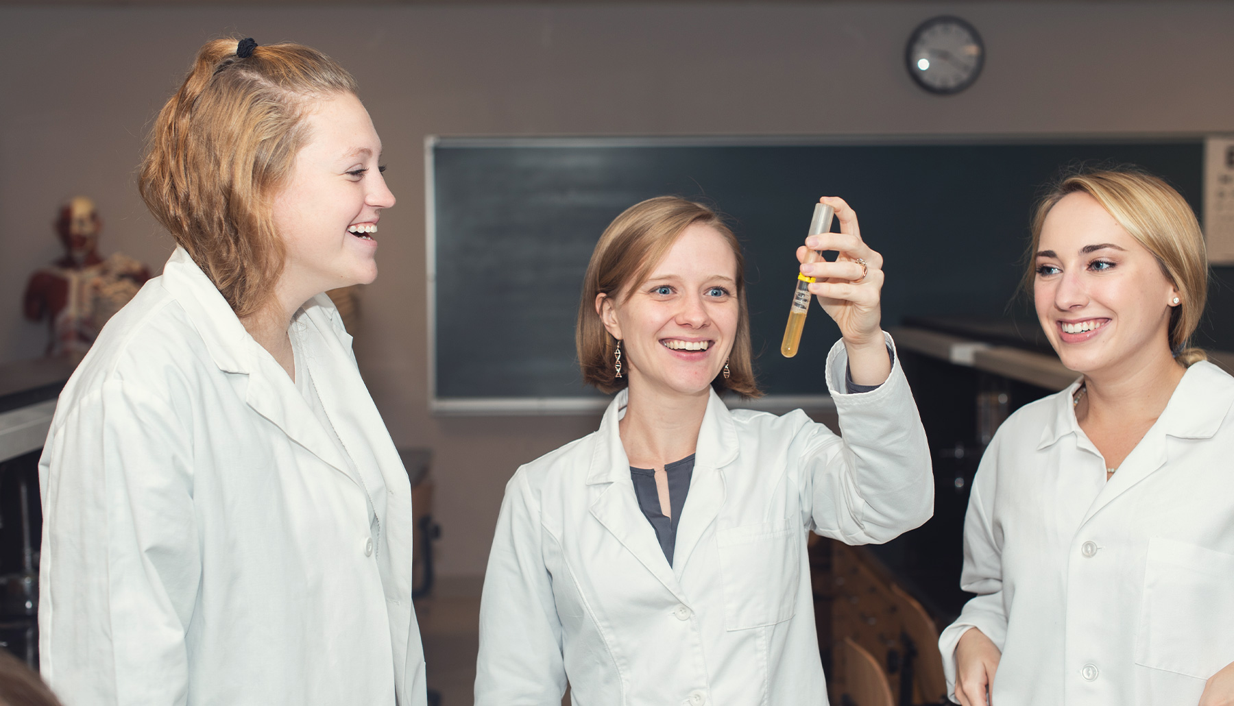 three women in lab coats look at a sample