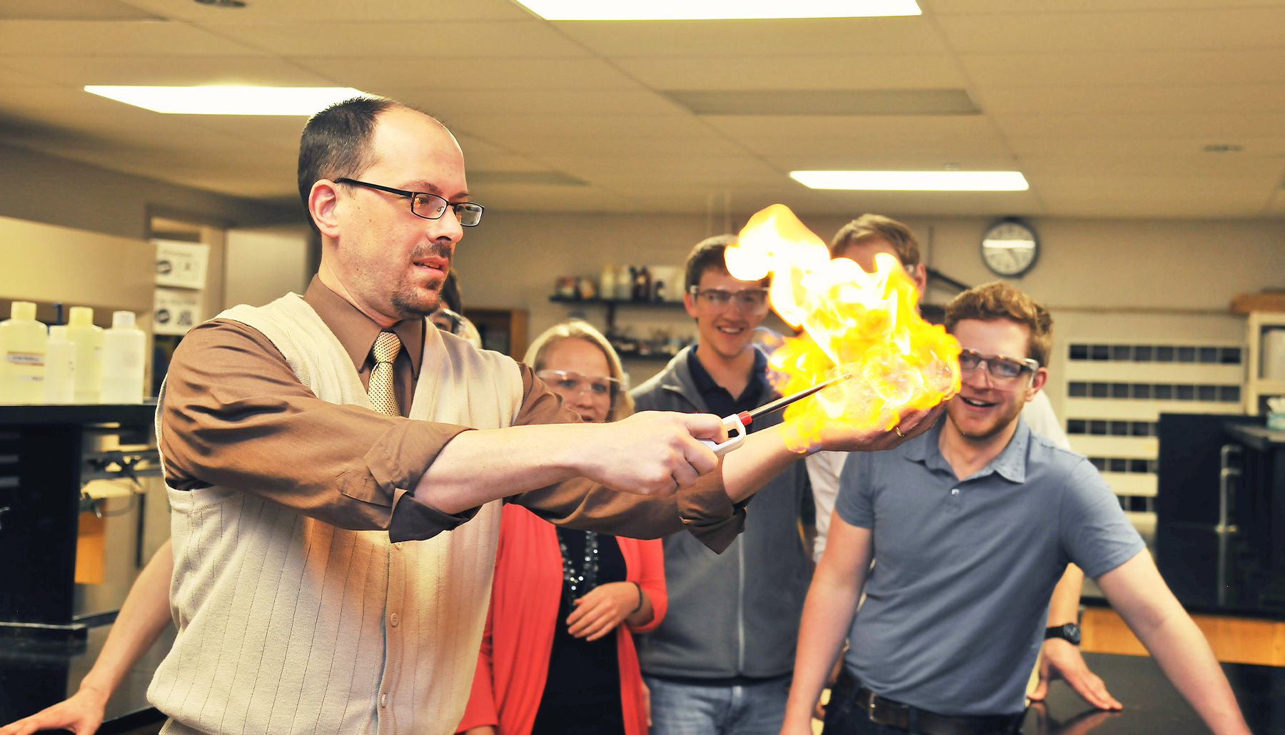 a male professor makes a fireball in his own hand while students watch