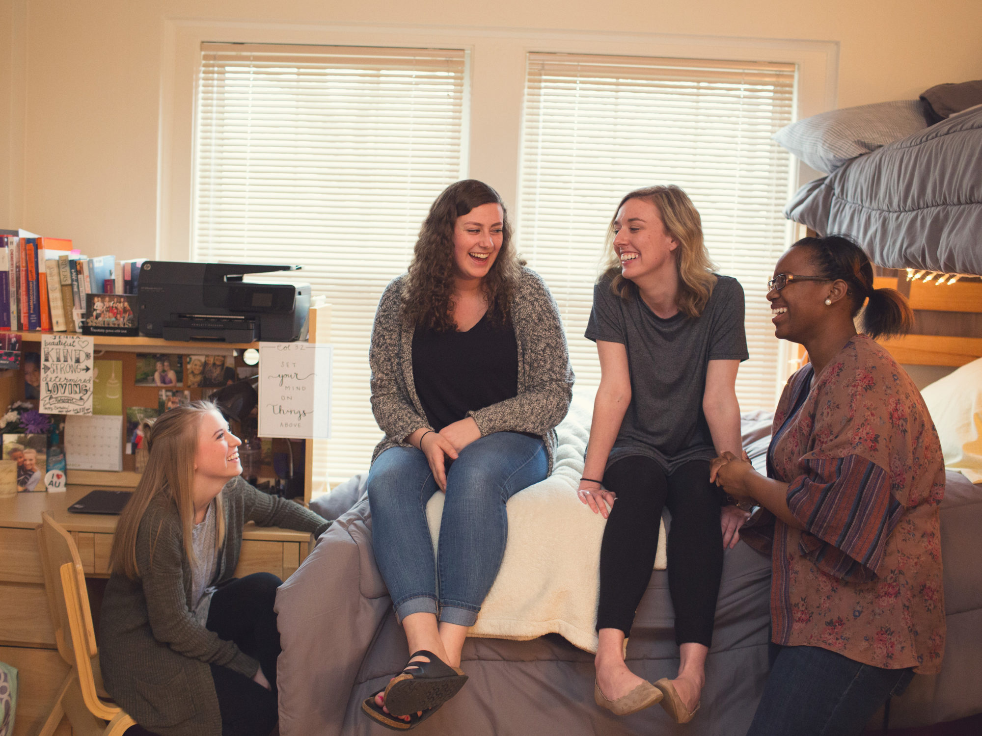 4 female students relaxing and talking in dorm room