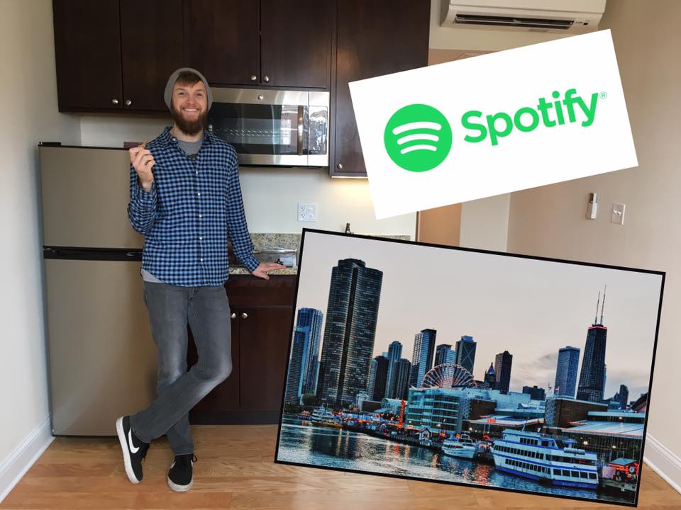 Gentleman in his apartment with the Spotify logo in the upper right and the Chicago skyline in the lower right