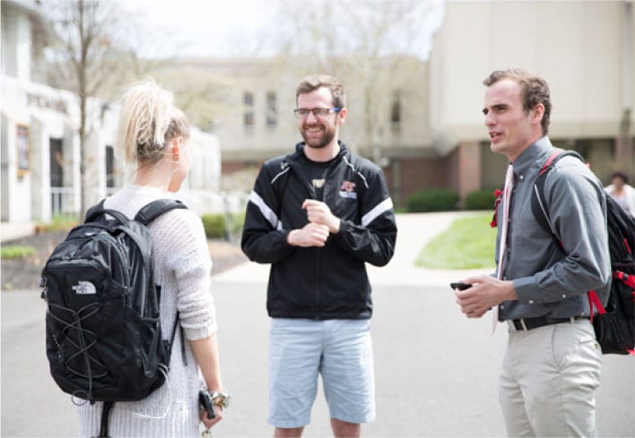 Two male students speaking with a female student outside of Byrum.