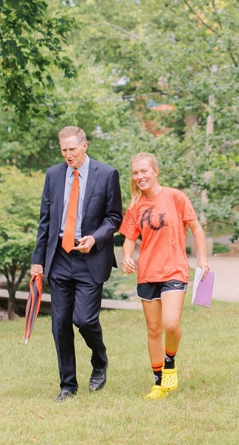 President Pistole and student walking at Anderson University Indiana