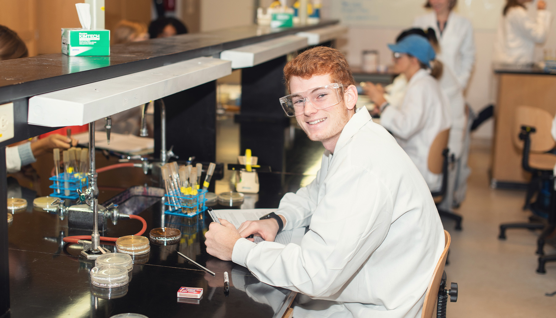 a young man in a lab coat and safety glasses