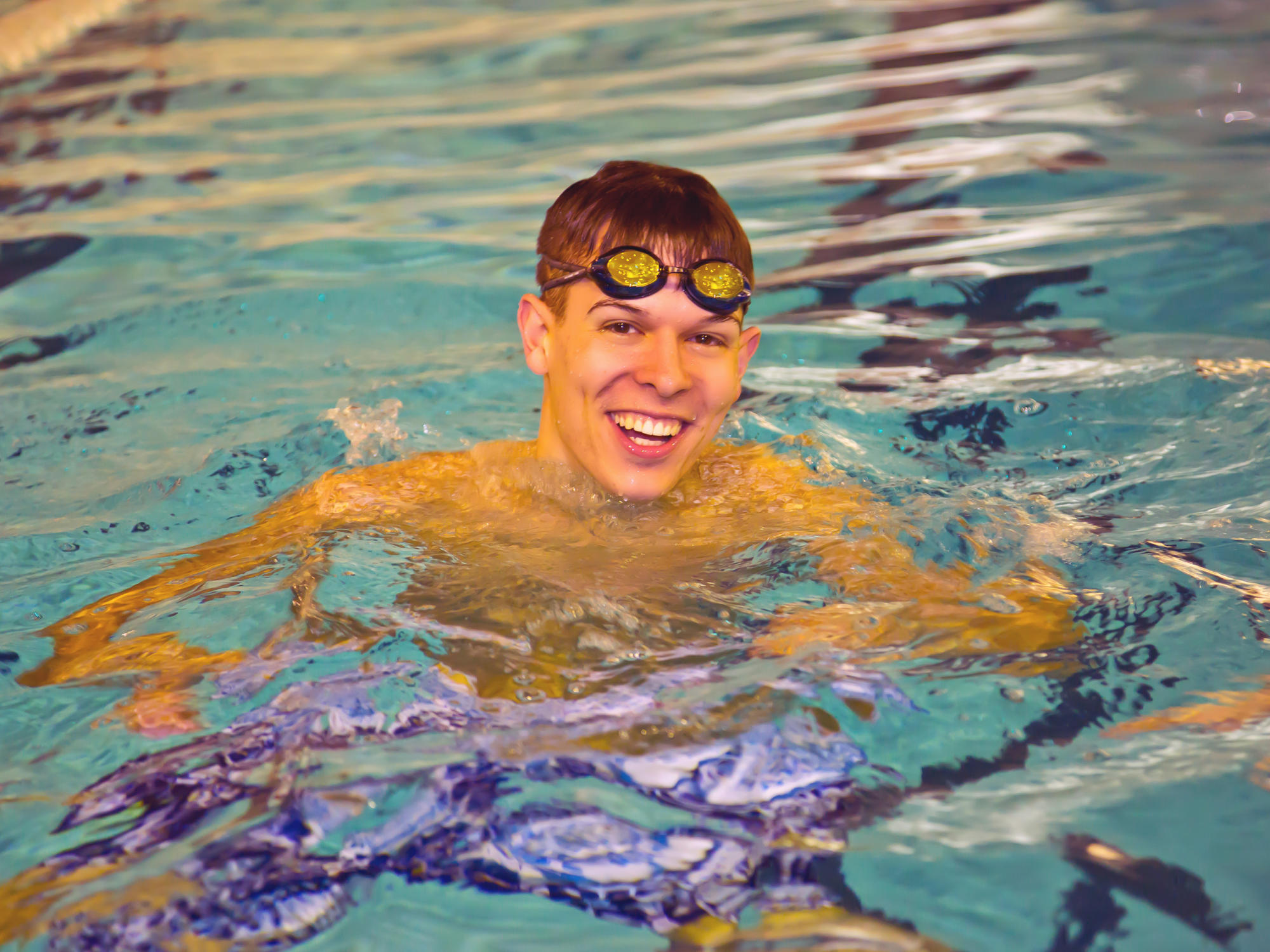 student in swimming pool with goggles on head
